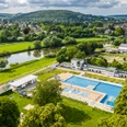 Luftaufnahme des Freibads Höxter im Grünen, umgeben von Bäumen und nahe am Fluss gelegen.
