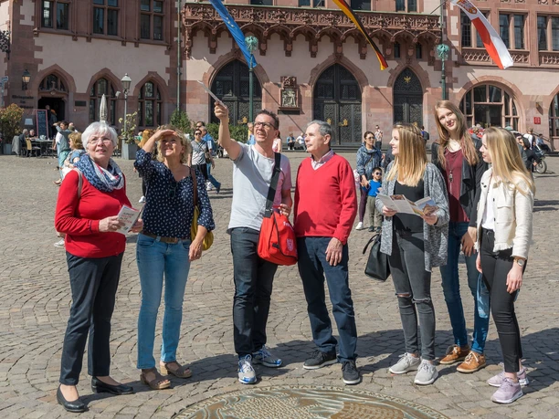 Stadtführung: Rundfahrt und Rundgang in Kombination Touristen-Gruppe erkundet bei Sonnenschein den Römerberg in Frankfurt.