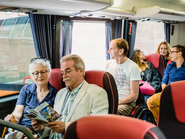 City tour: tour by bus and walking tour in combination Tour group on the bus discovering Frankfurt in a relaxed manner with city map in hand.