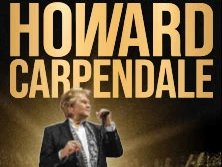 Howard Carpendale während seiner Abschiedstournee auf einer Bühne im Rampenlicht, singend und gestikulierend.