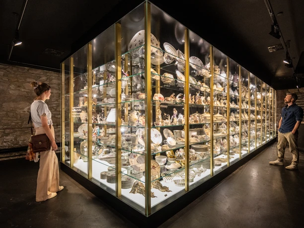 Museumsausstellung im Schloss Fürstenberg mit vielfältigen Porzellanobjekten, Besucher betrachten Vitrine.