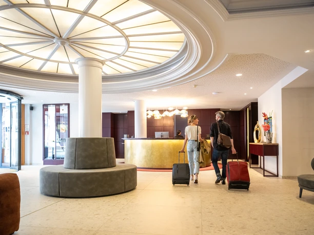 Hoexter-Hotel-Teutoburger-Wald-Stadt-Hoexter-D-Ketz-023.jpg Ein elegantes Hotelfoyer in Höxter mit großem Lichtelement an der Decke und einladendem Empfangsbereich.