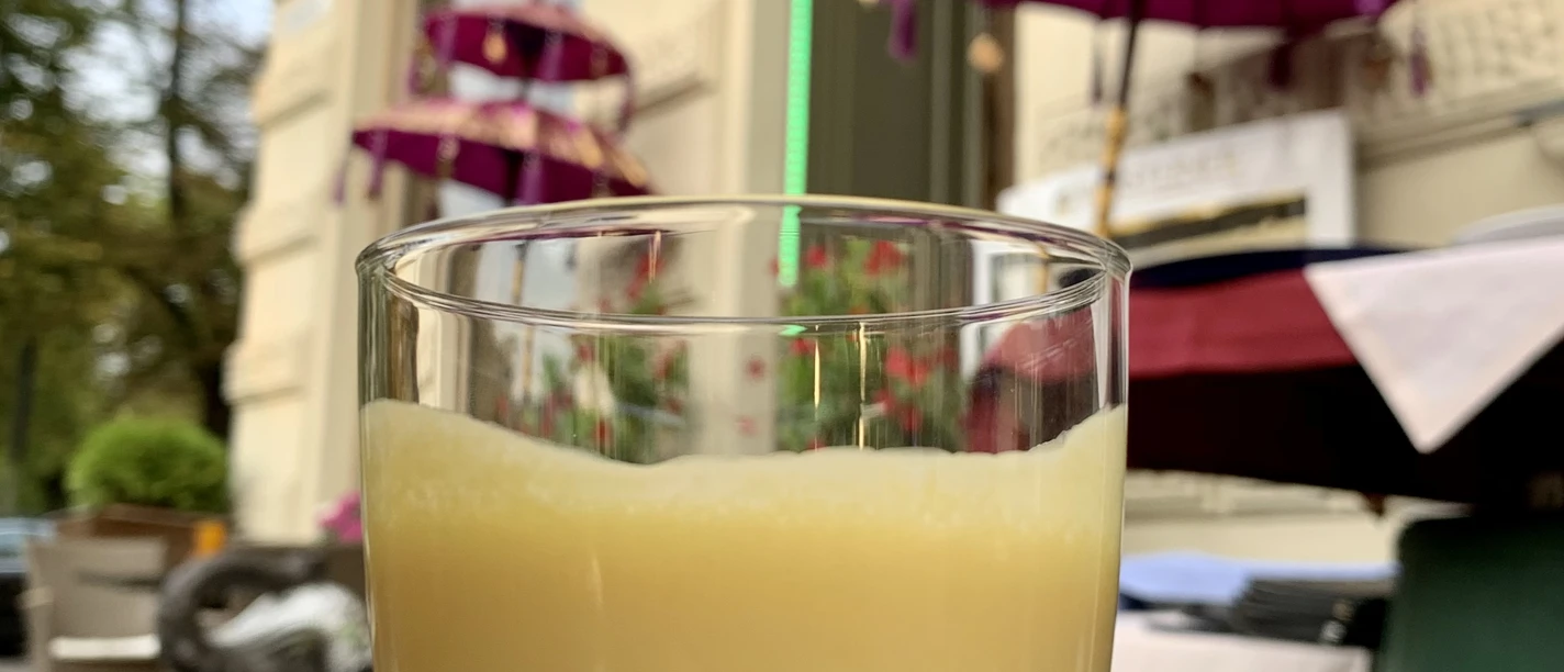 Altstadt Genusstour Ein mit Mango-Lassi gefüllten Glas steht auf einem Tisch im Außenbereich eines Restaurants.