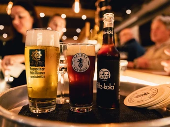 Getränkeauswahl im Bürgerhaus Ratingen Bierglas, Glas mit dunklem Getränk und Flasche Fritz-Kola auf einem Tablett in geselliger Runde.