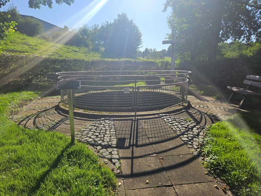 Heiligenteich Pömbsen Heiligenteich mit Grünflächen und einer Bank im sonnigen Licht.