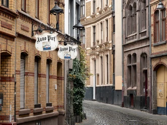 Gepflasterte Straße mit historischen Gebäuden und Laternen in einer ruhigen Altstadt-Straße.