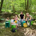 GruenesKlassenzimmer_am_Bodenprofil_Provinzialmoor_VS_2.jpg Kinder und Erwachsene sitzen im Wald auf grünen Holzhockern und lernen gemeinsam im Freien.