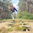 WesuweerWald_Aktiv-Pfad©NaturparkMoor_VSchepers.JPEG Frau balanciert auf Übungselementen entlang eines Naturpfads im bewaldeten Wesuweer Wald.