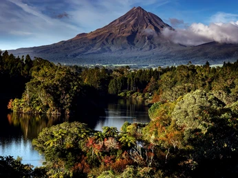 Pressebild Neuseeland - Lake Mangamahoe und Mount Taranaki 2.JPG Vulkan Mount Taranaki über dichtem Wald und ruhigem See unter blauem Himmel mit leichten Wolken.