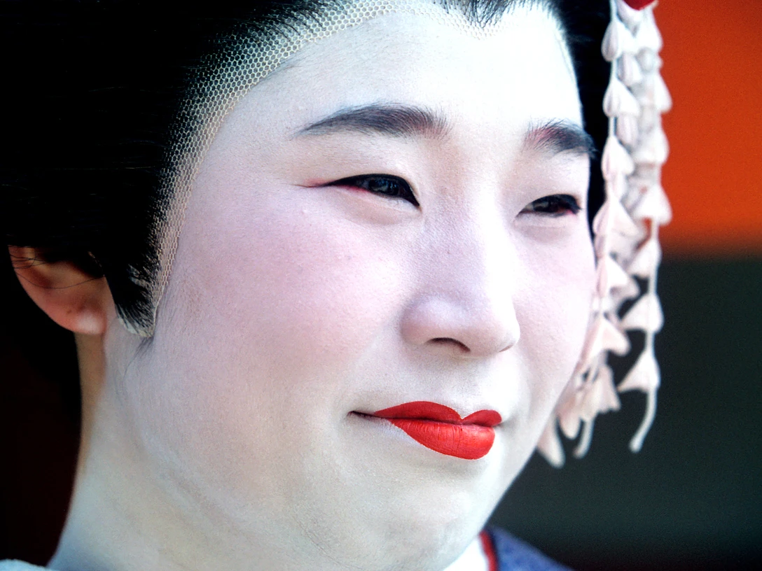 Pressebild Japan - Geisha.jpg Nahaufnahme einer Person mit traditionellem weißen Make-up, rotem Lippenstift und Haarschmuck