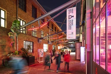 MACHWERKHAUS Lively art center at night with red brick walls, people enter through the entrance.