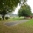 Boulebahn in Würgassen Eine Boulebahn auf einer Wiese mit Bäumen und einem Spielplatz im Hintergrund..