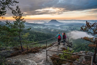 Sunset on the Papststein Two hikers watch the sunset from a vantage point in the Elbe Sandstone Mountains.