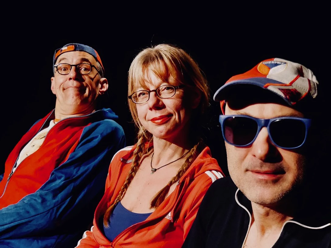 251203_JStaidelCombo.jpg Drei Personen in sportlicher Kleidung und Sonnenbrillen blicken lächelnd in die Kamera vor schwarzem Hintergrund.