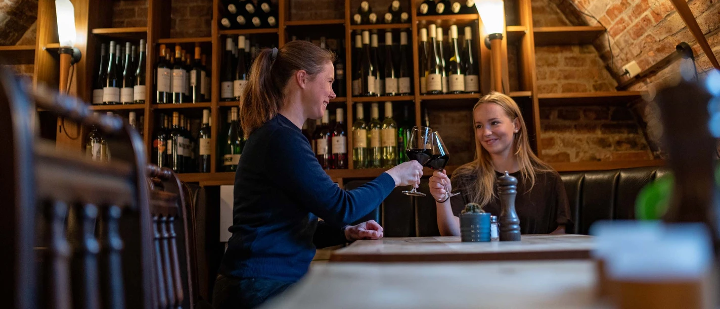 Eutin-Gastronomie-Bacchuskeller-Gewölbe.jpg Zwei Freundinnen stoßen mit Weingläsern im Gewölbe des Bacchuskellers in Eutin an