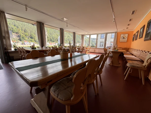 Uitnodigende eetzaal van restaurant "Zum Echtner" met houten tafels, fauteuils en een groot raam met uitzicht.