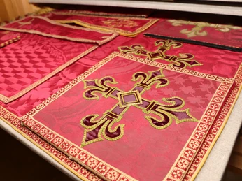 Kreuzförmige und geometrische Stickmuster auf rotem Stoff.