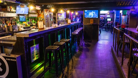 Lost Level bar area Elongated bar area with bar stools in subdued lighting. Televisions on the walls.