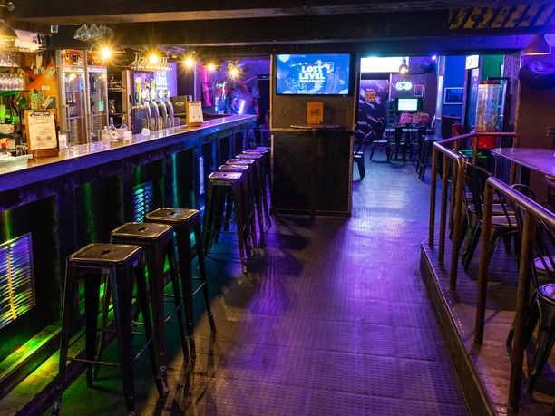 Lost Level bar area Elongated bar area with bar stools in subdued lighting. Televisions on the walls.