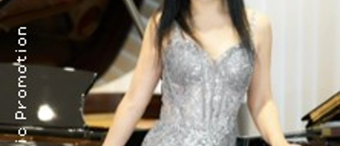 Porträt einer lächelnden Musikerin in einem silbernen Kleid vor einem Flügel, elegant posierend.