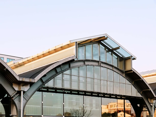 Design Post Modern building with glass façade, arched structures and dry grass in the foreground.