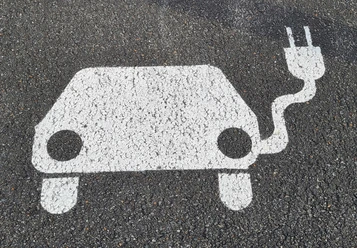 Symbol E-Auto mit Aufladekabel auf Asphalt