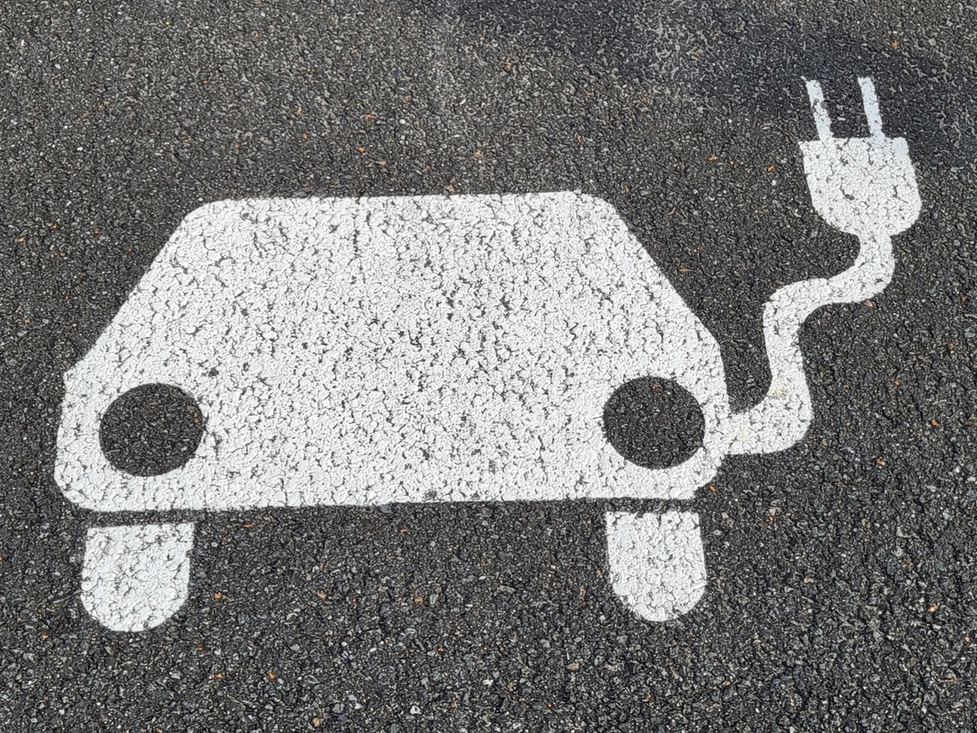 Symbol E-Auto mit Aufladekabel auf Asphalt