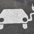 Symbol E-Auto mit Aufladekabel auf Asphalt
