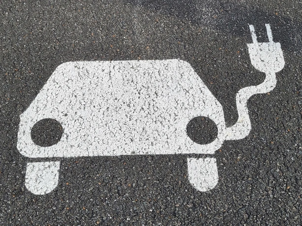 Symbol E-Auto mit Aufladekabel auf Asphalt
