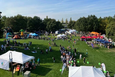 Weltkindertag, Mülheim an der Ruhr Weltkindertag in der MüGa: Der Park ist voller bunter Stände, Menschenmengen und Ballons bei blauem Himmel.