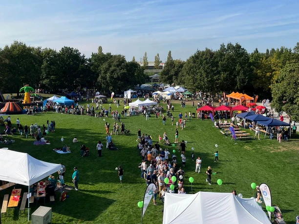 Weltkindertag, Mülheim an der Ruhr Weltkindertag in der MüGa: Der Park ist voller bunter Stände, Menschenmengen und Ballons bei blauem Himmel.