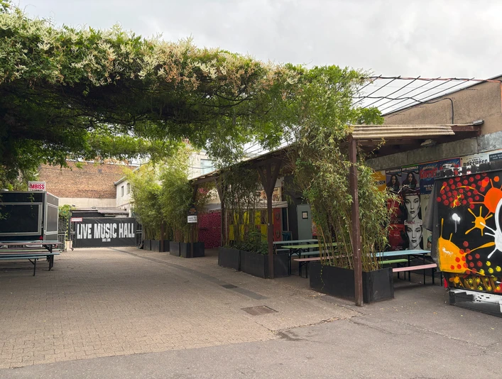 Live Music Hall Außenbereich der Live Music Hall mit bunten Graffiti, Bambuspflanzen und Sitzmöglichkeiten.Outdoor area of the Live Music Hall with colorful graffiti, bamboo plants and seating.