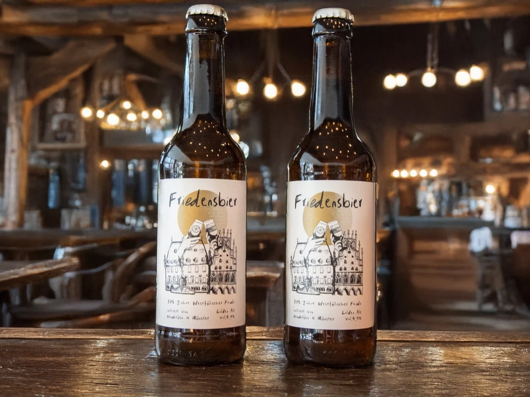 Beschwipster Nachtwächter (Hauptbild).jpg Zwei Flaschen Friedelnsbier stehen in einem rustikalen Wirtshaus mit stimmungsvoller Beleuchtung.