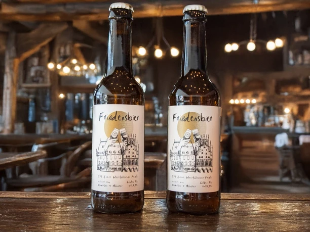 Beschwipster Nachtwächter (Hauptbild).jpg Zwei Flaschen Friedelnsbier stehen in einem rustikalen Wirtshaus mit stimmungsvoller Beleuchtung.
