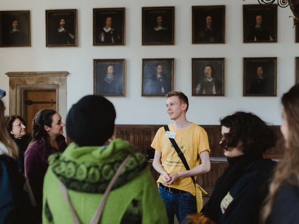 Rathaus- und Altstadt (2).jpg A group of people stand in a historical room with a guide, surrounded by portrait paintings.