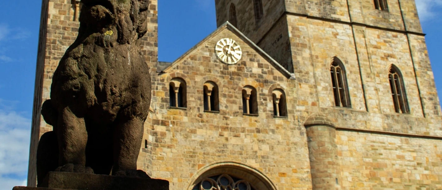 Altstadt-Highlights (Hauptbild).jpg Stenskulptur af en løve foran en historisk kirke med to tårne og et stort ur.