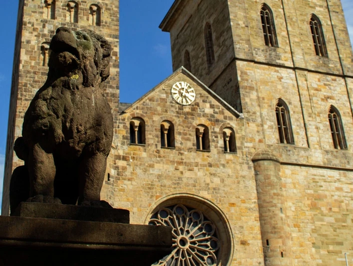 Altstadt-Highlights (Hauptbild).jpg Steinerne Skulptur eines Löwen vor einer historischen Kirche mit zwei Türmen und einer großen Uhr.Stone sculpture of a lion in front of a historic church with two towers and a large clock.Stenen beeld van een leeuw voor een historische kerk met twee torens en een grote klok.