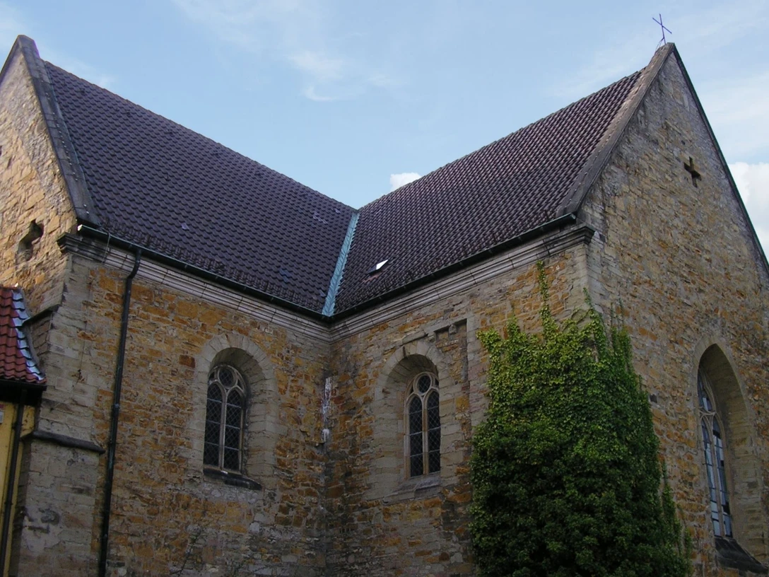 Gertrudenberg (Hauptbild).jpg Historische Kirchenmauer aus Backstein, flankiert von Fenstern mit gotischem Stil, bewachsen mit Efeu.Historic brick church wall, flanked by Gothic-style windows, overgrown with ivy.Historische bakstenen kerkmuur, geflankeerd door ramen in gotische stijl, overwoekerd door klimop.