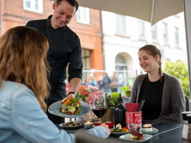 Eutin_Gastro_Stumpfes Eck_Marktterrasse.jpg Zwei Freundinnen sitzen auf der Marktterrasse des Bistros Stumpfes Eck in Eutin und bekommen Tapas serviert