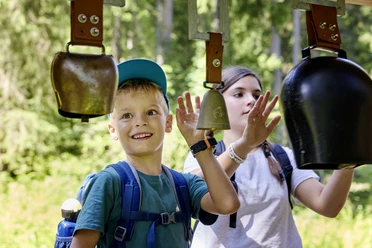 2024-08-28 Goldi Gwundernasenweg (26).jpg Ein Junge und ein Mädchen am Glockenspiel beim Goldi-Gwundernasenweg auf der Klewenalp-Stockhütte
