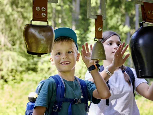 2024-08-28 Goldi Gwundernasenweg (26).jpg Ein Junge und ein Mädchen am Glockenspiel beim Goldi-Gwundernasenweg auf der Klewenalp-Stockhütte