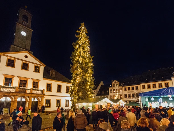 Weihnachtsmarkt Rochlitz - Weihnachten in der Region Leipzig Auf dem Weihnachtsmarkt in Rochlitz flanieren Menschen zwischen festlich erleuchtetem Tannenbaum und Ständen.