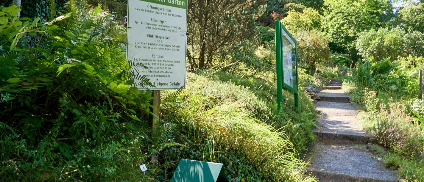 Botanischer Garten Bad Schandau Entrance to the Bad Schandau Botanical Gardens with information sign next to a shady path.