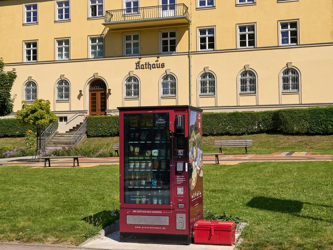 Proviantomat Bad Schandau Elbkai Busbahnhof Verkaufsautomat vor historischer Rathausfassade in Bad Schandau, umgeben von Grünflächen.