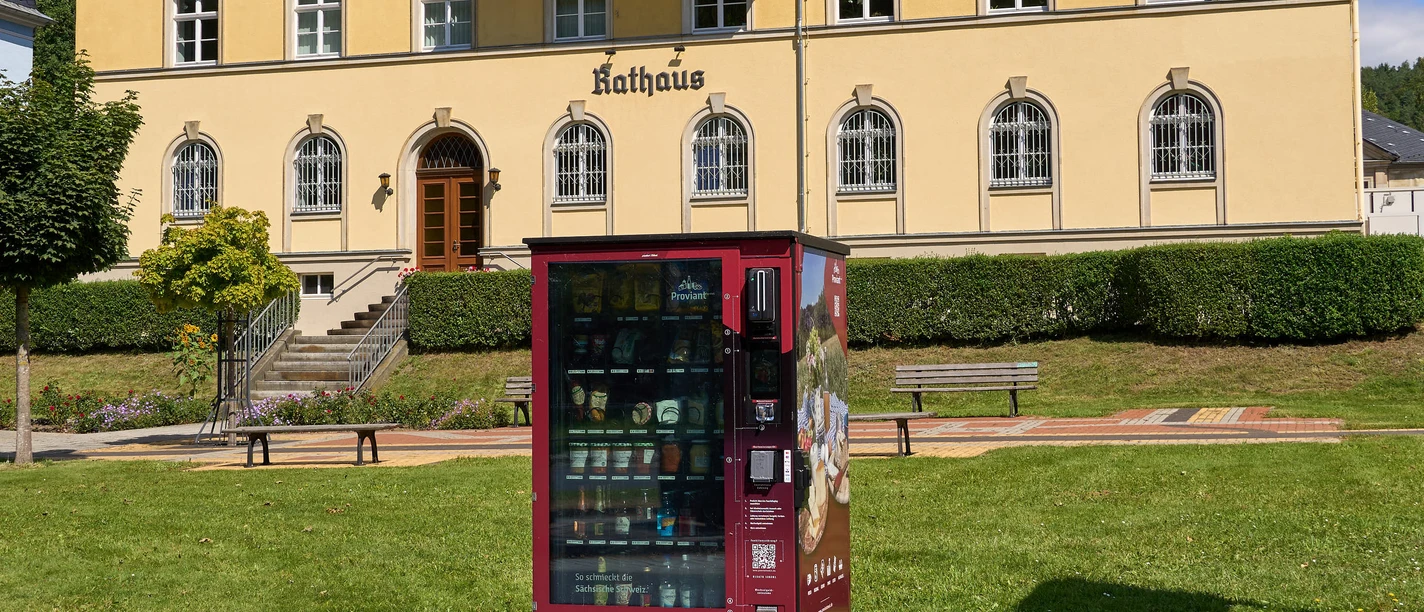 Proviantomat Bad Schandau Elbkai Busbahnhof Verkaufsautomat vor historischer Rathausfassade in Bad Schandau, umgeben von Grünflächen.