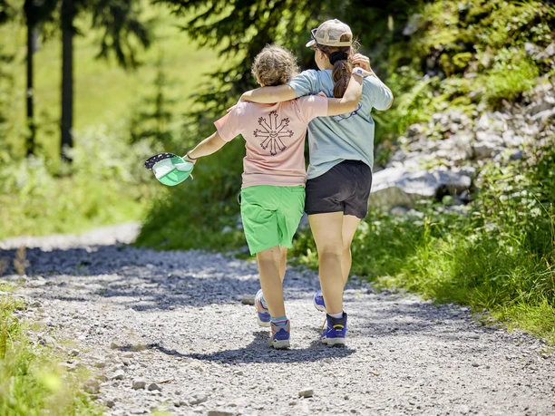 LU_Tourismus_Emmetten_BB_11.8.25_26.jpg Zwei Mädchen fotografiert von hinten am Wandern auf der Stockhütte bei Sonnenschein.