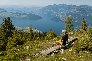 Ein Wanderer geniesst die Aussicht auf einer Bank auf dem Stollen auf der Klewenalp.