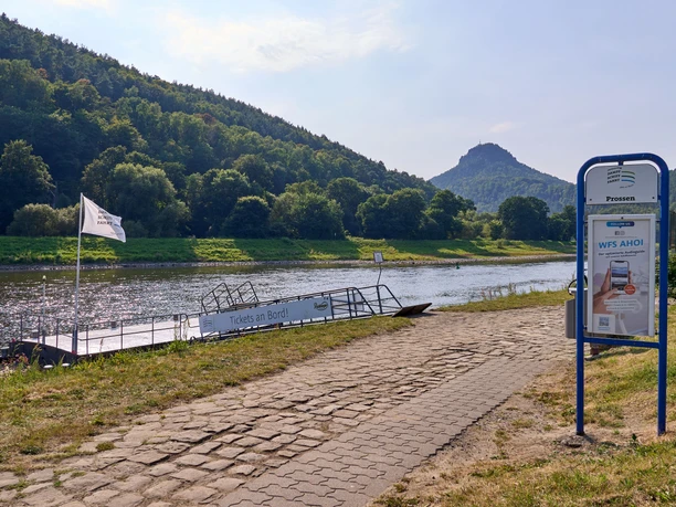 Steamboat jetty in Prossen on the Elbe with a view of wooded hills in the background.