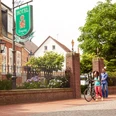 Radler vor Haus Russell vom Burghotel in Haselünne - Radfahren im Emsland ©Emsland Tourismus GmbH (2).jpg Zwei Radfahrer gehen vor dem historischen Burghotel Haselünne entlang einer Baumallee im Emsland.