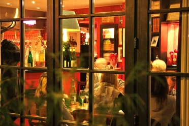 Weihnachtlich1.jpg Ein Blick durch Fenster auf ein festlich beleuchtetes Restaurant mit Gästen am Tisch.